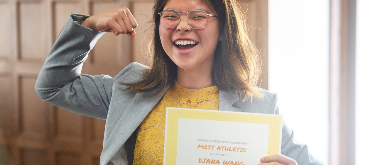 Diana Wang smiling and holding a certificate that reads "Most Athletic - Diana Wang"