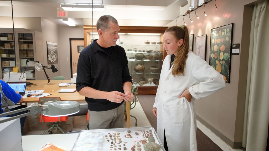 Two people standing and talking in front of geological samples